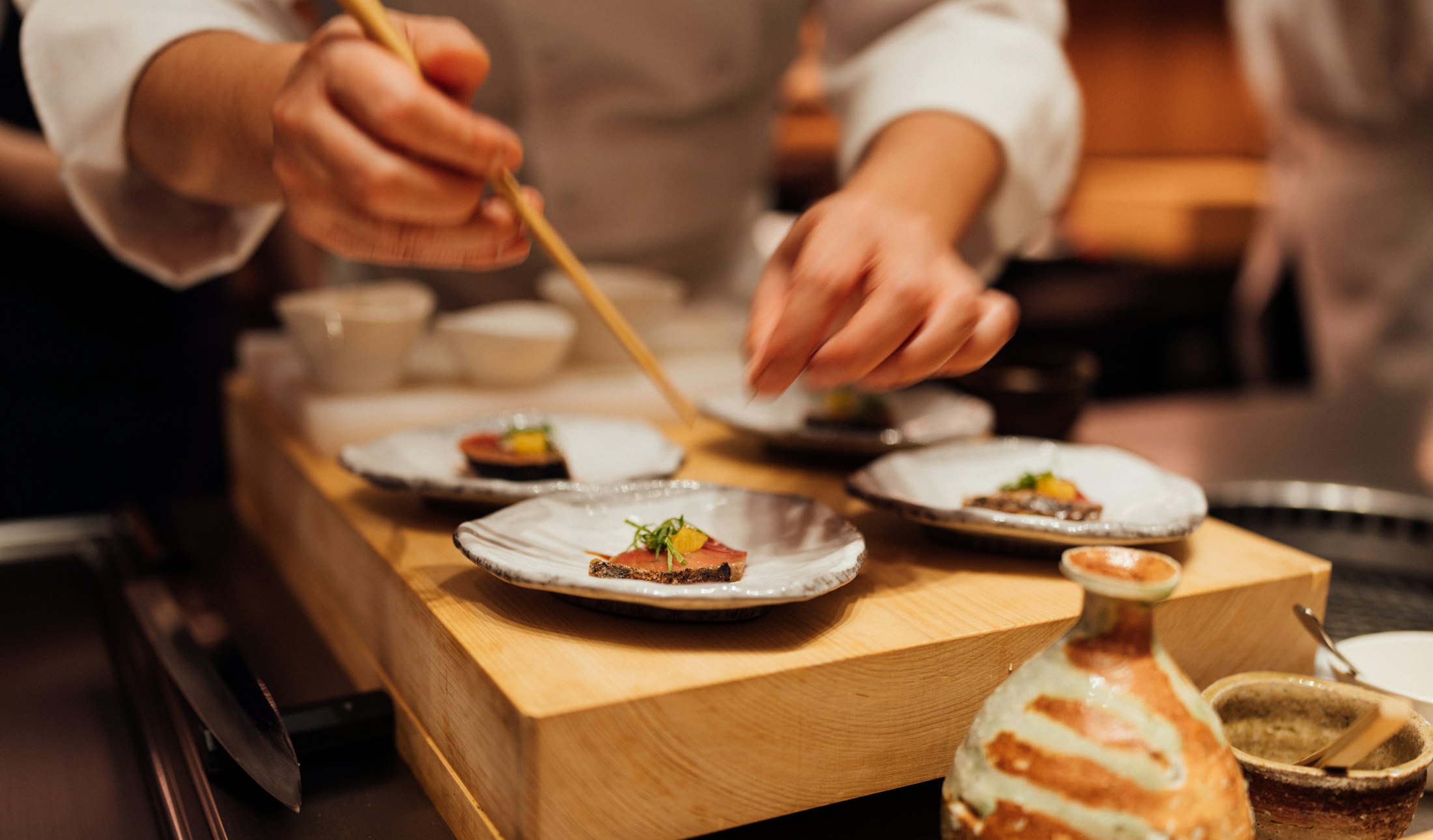 料理人の手が木の台の上で料理を仕立てている様子